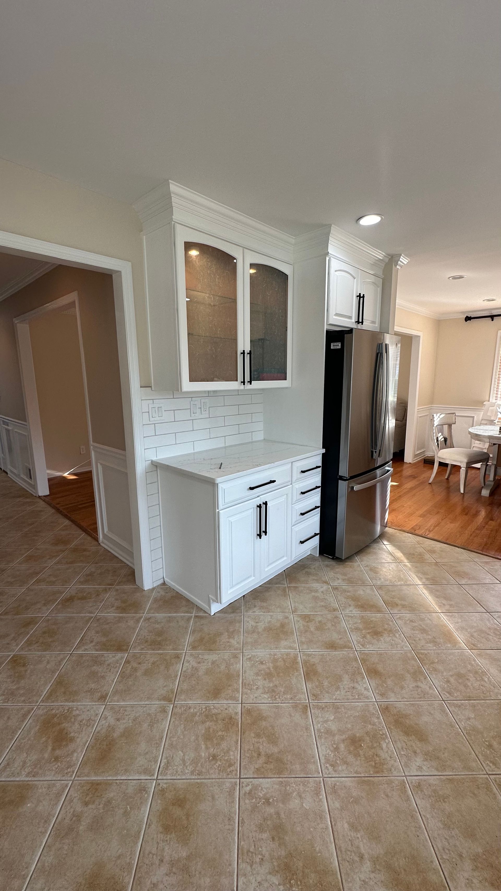 A kitchen with white cabinets , stainless steel appliances , a refrigerator and a sink.