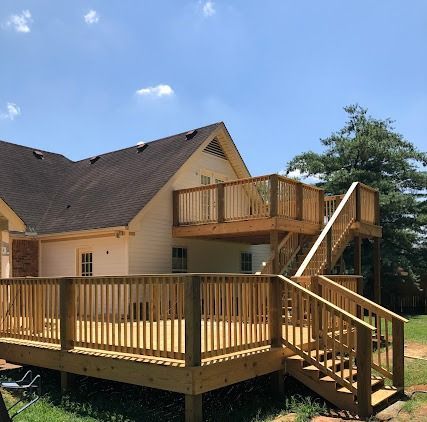 Wooden deck on the back of a house, with stairs to a second-story deck. Sunny day, blue sky.