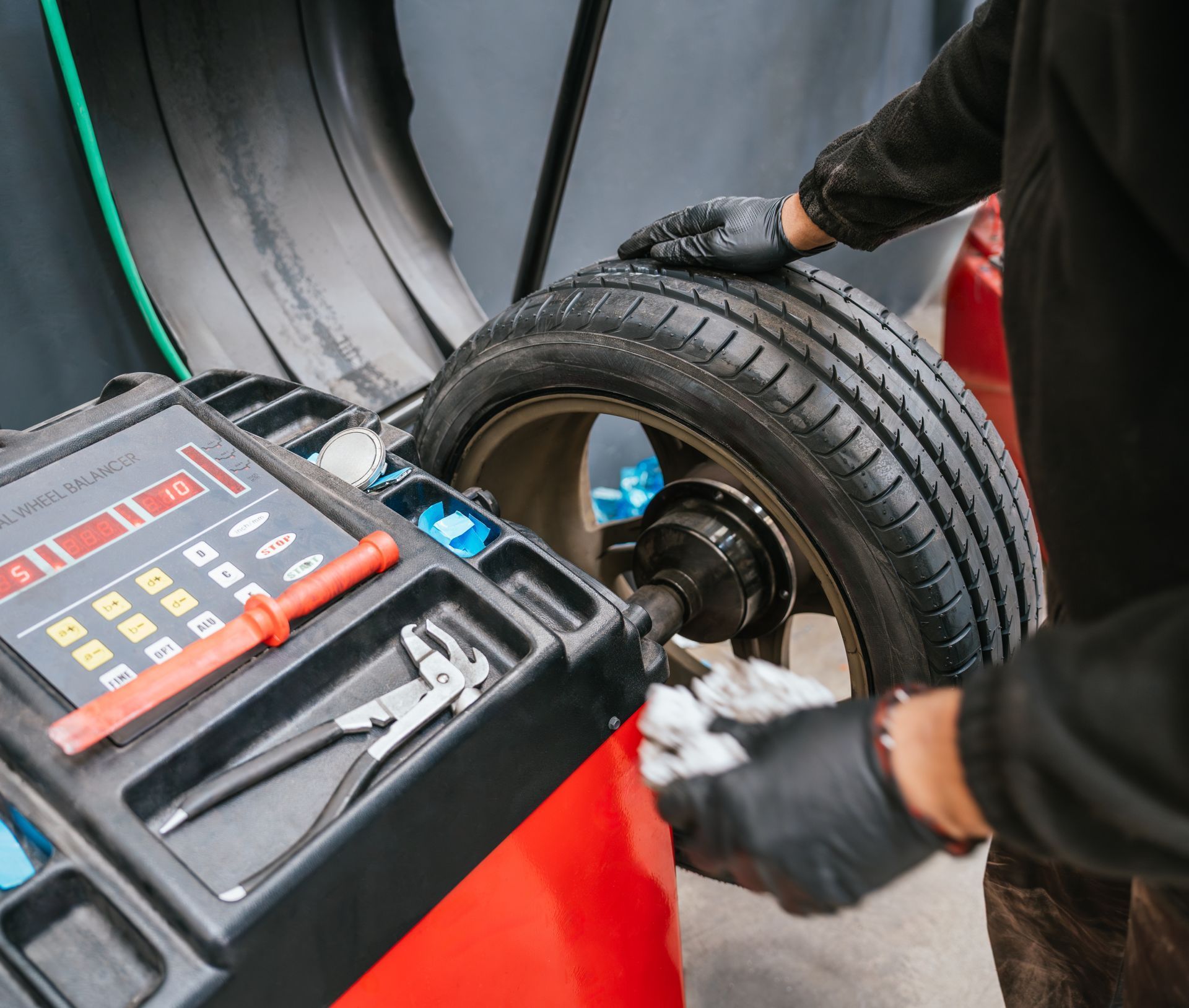 A mechanic balancing a tire on a machine in a garage.
