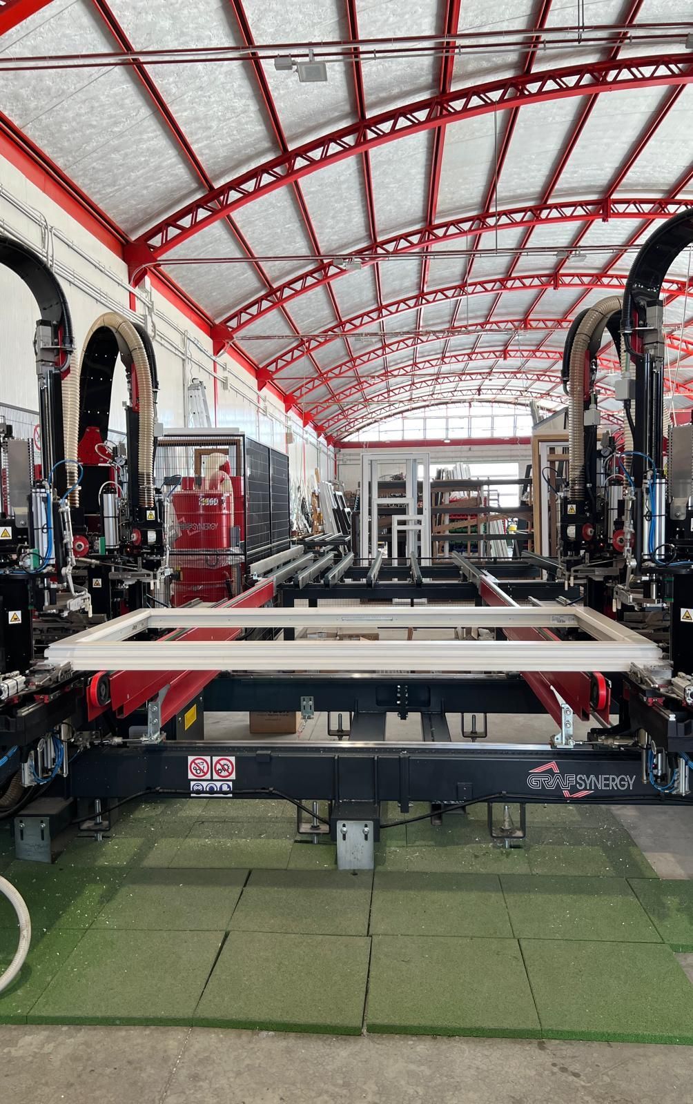 Telaio di una finestra su una linea di montaggio robotizzata in un edificio industriale rosso e bianco.