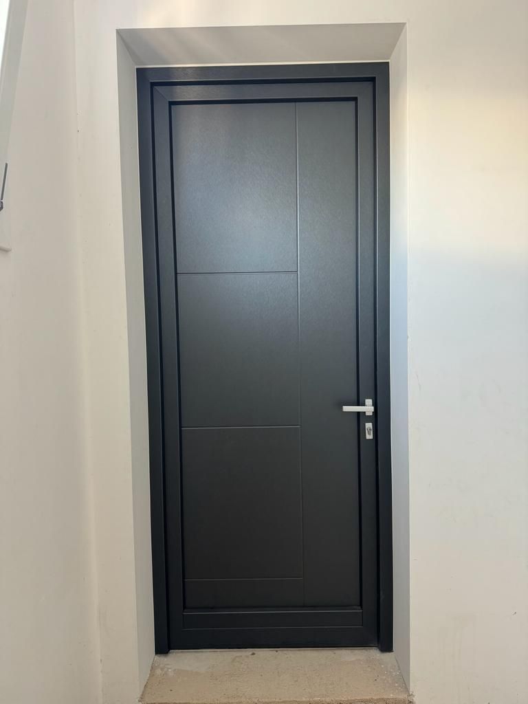 Porta nera con dettagli a pannelli orizzontali e verticali su un vano porta bianco, maniglia argentata.