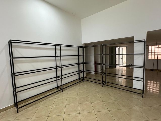 Scaffale in metallo nero in una stanza vuota con pareti bianche e pavimento piastrellato.