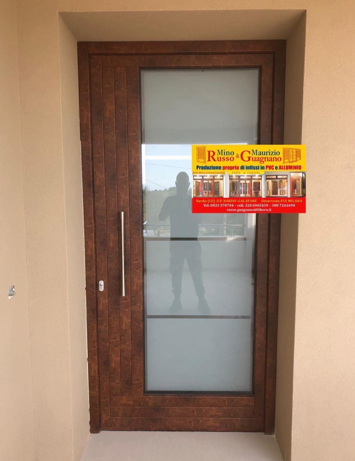 Porta d'ingresso in legno con pannelli in vetro smerigliato e una lunga maniglia argentata