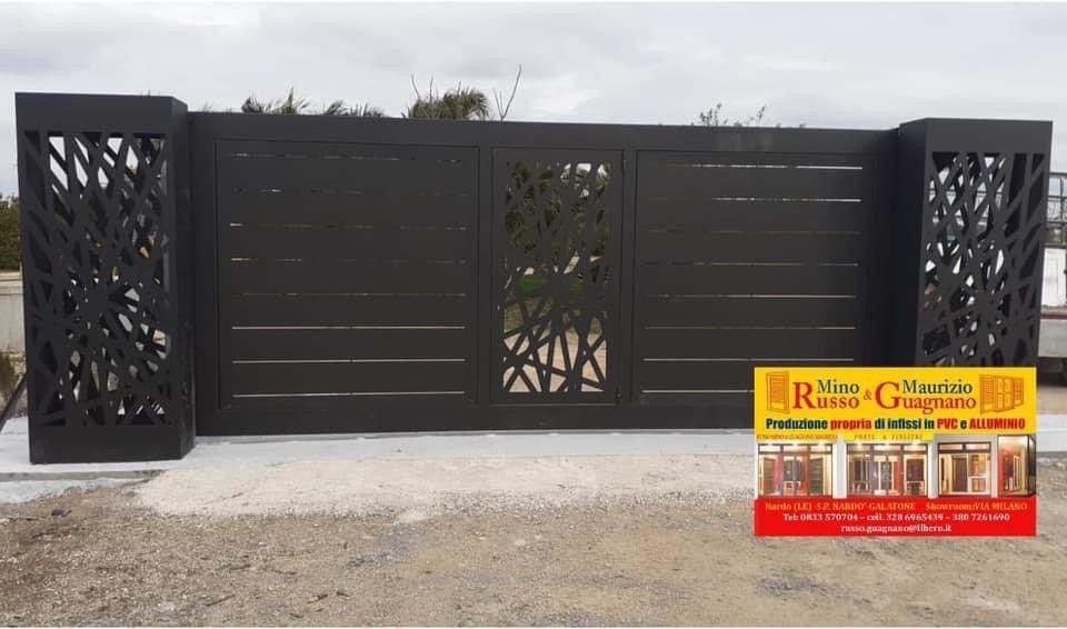 Cancello in metallo nero con colonne laterali decorative e pannello centrale.