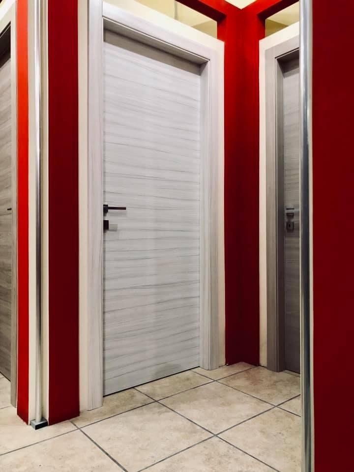 Porte interne in un corridoio con pareti rosse e pavimento piastrellato.