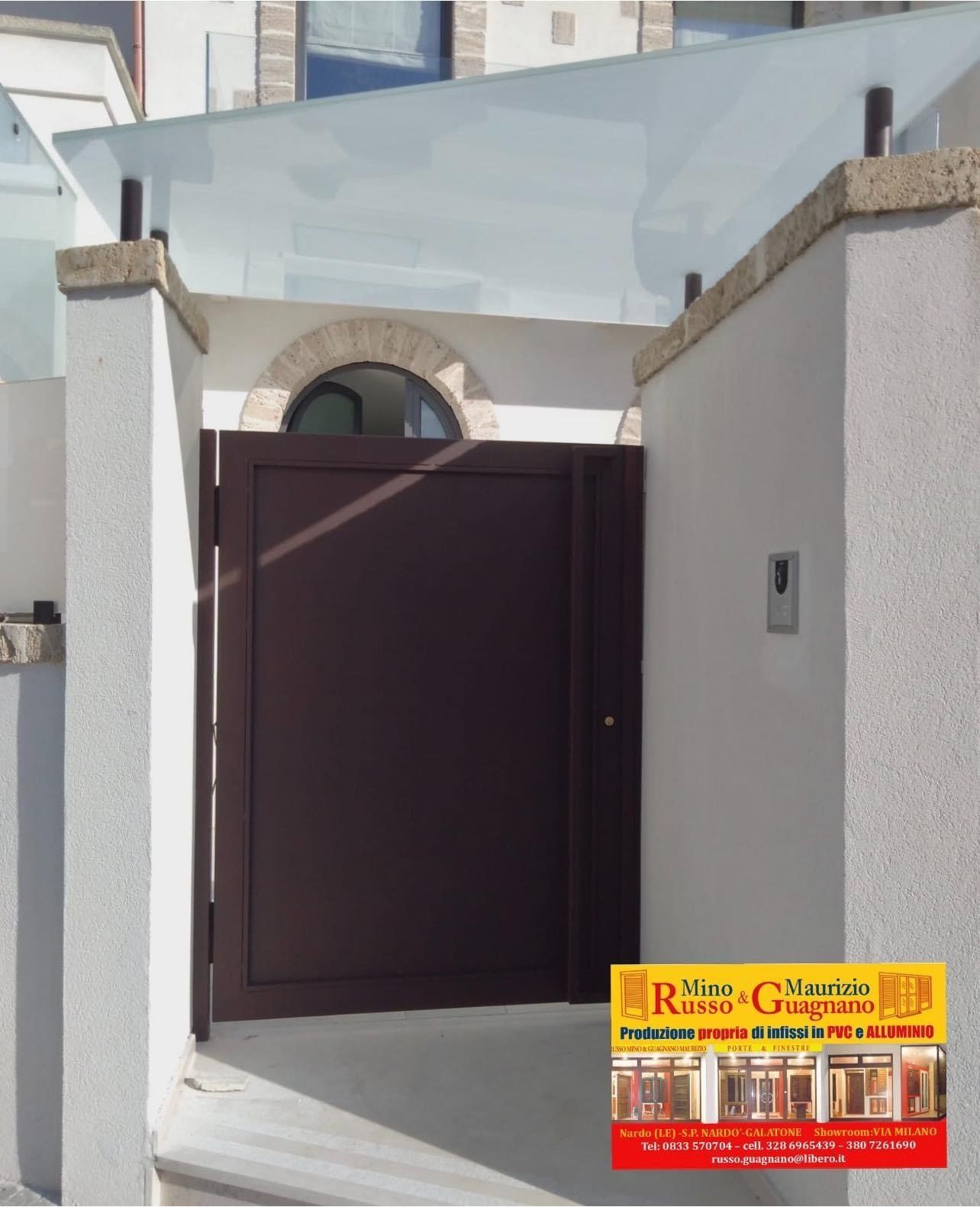 Cancello marrone in un muro di stucco bianco, con tetto in vetro, arco in pietra 