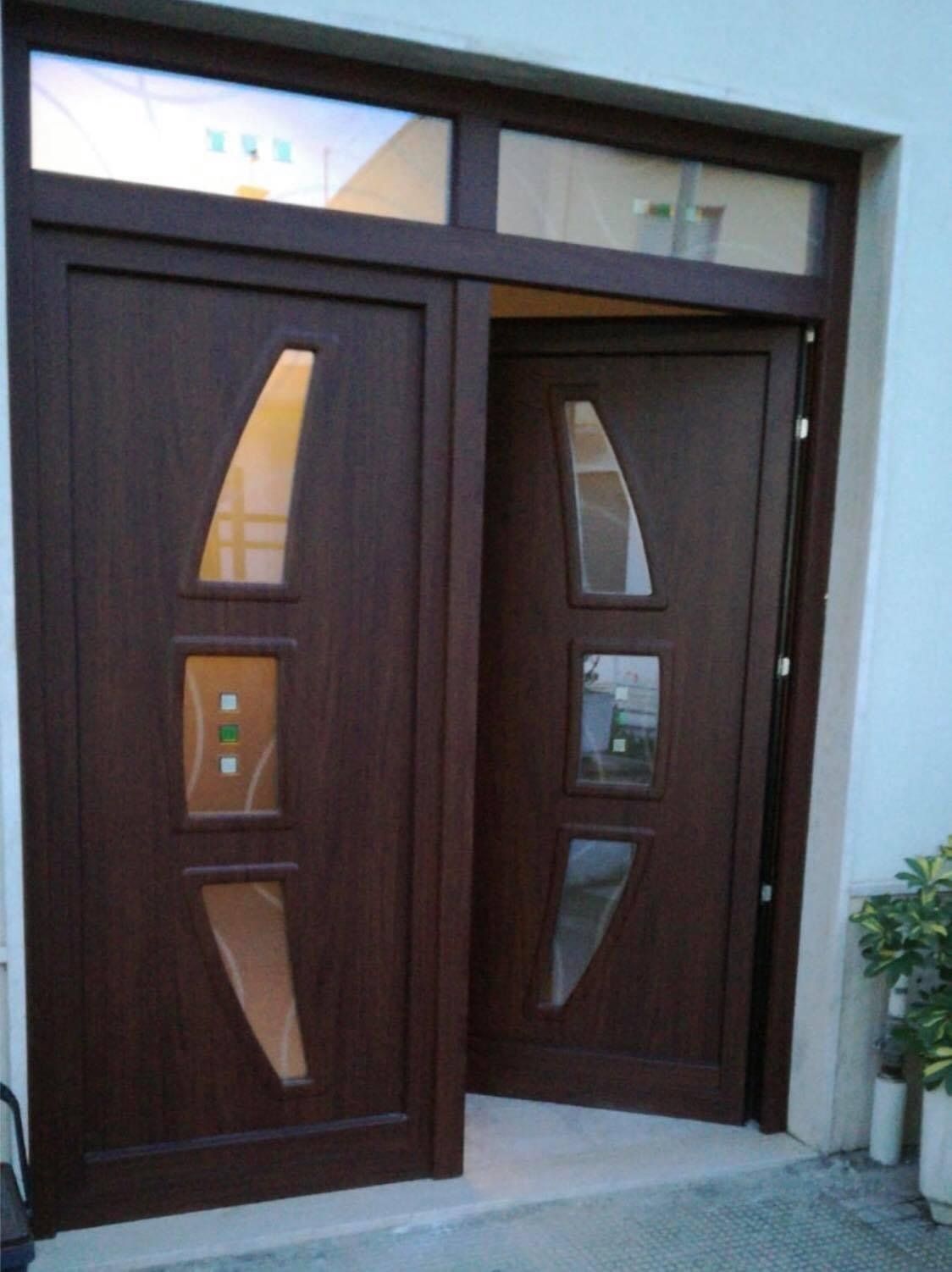 Porte d'ingresso doppie marroni con pannelli in vetro e una finestra a traversa.
