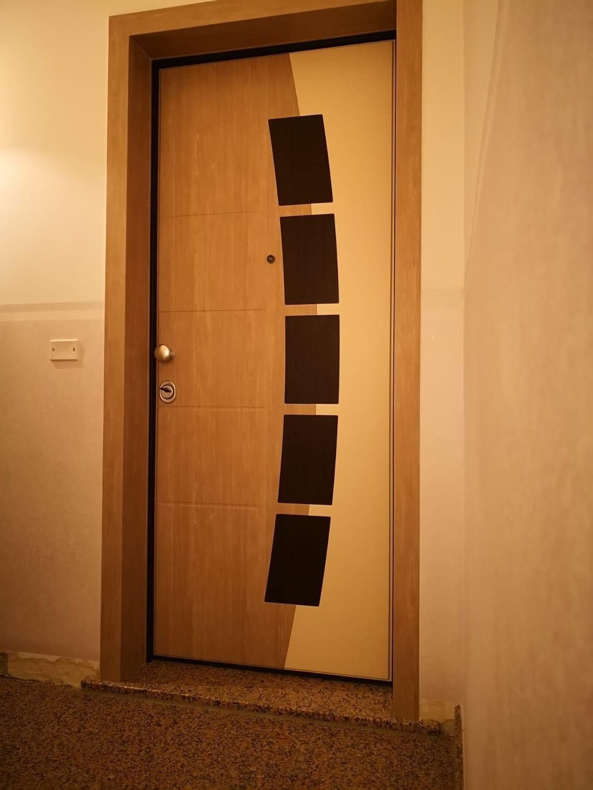 Porta in legno con finestra curva nera, inserita in un corridoio dai colori chiari.