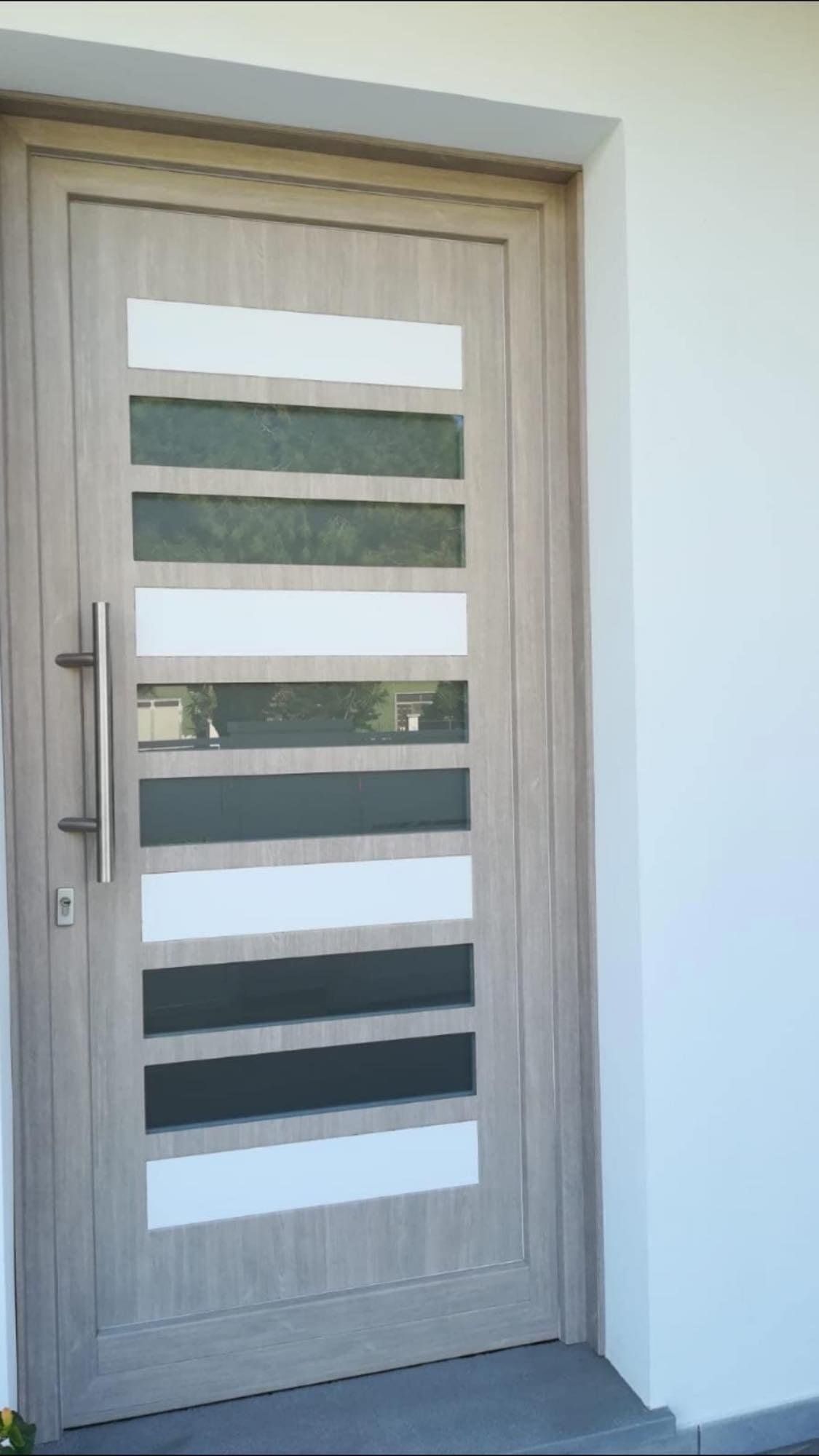 Porta d'ingresso beige con vetri orizzontali, bianchi e sfumati. Maniglia argentata.