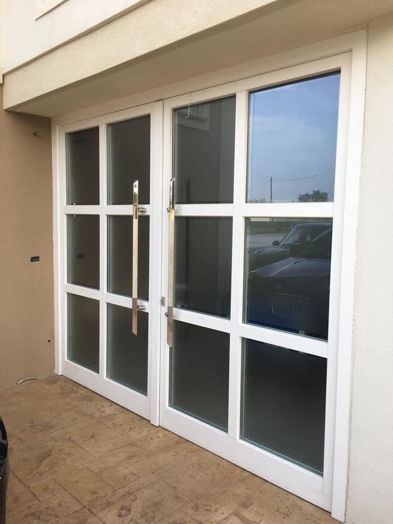 Porte in vetro con pannelli bianchi e maniglie argentate; esterno dell'edificio.