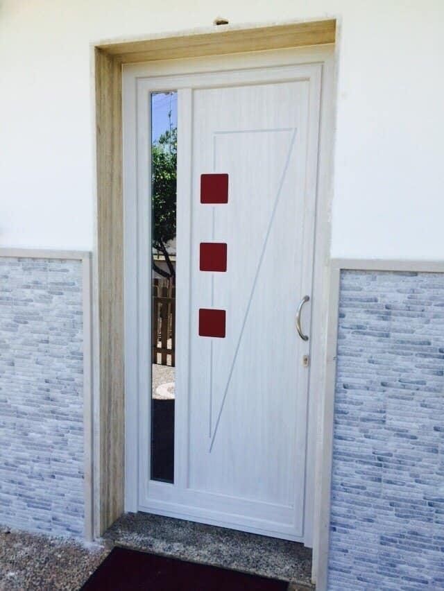 Porta bianca con un pannello di vetro e tre quadrati rossi.