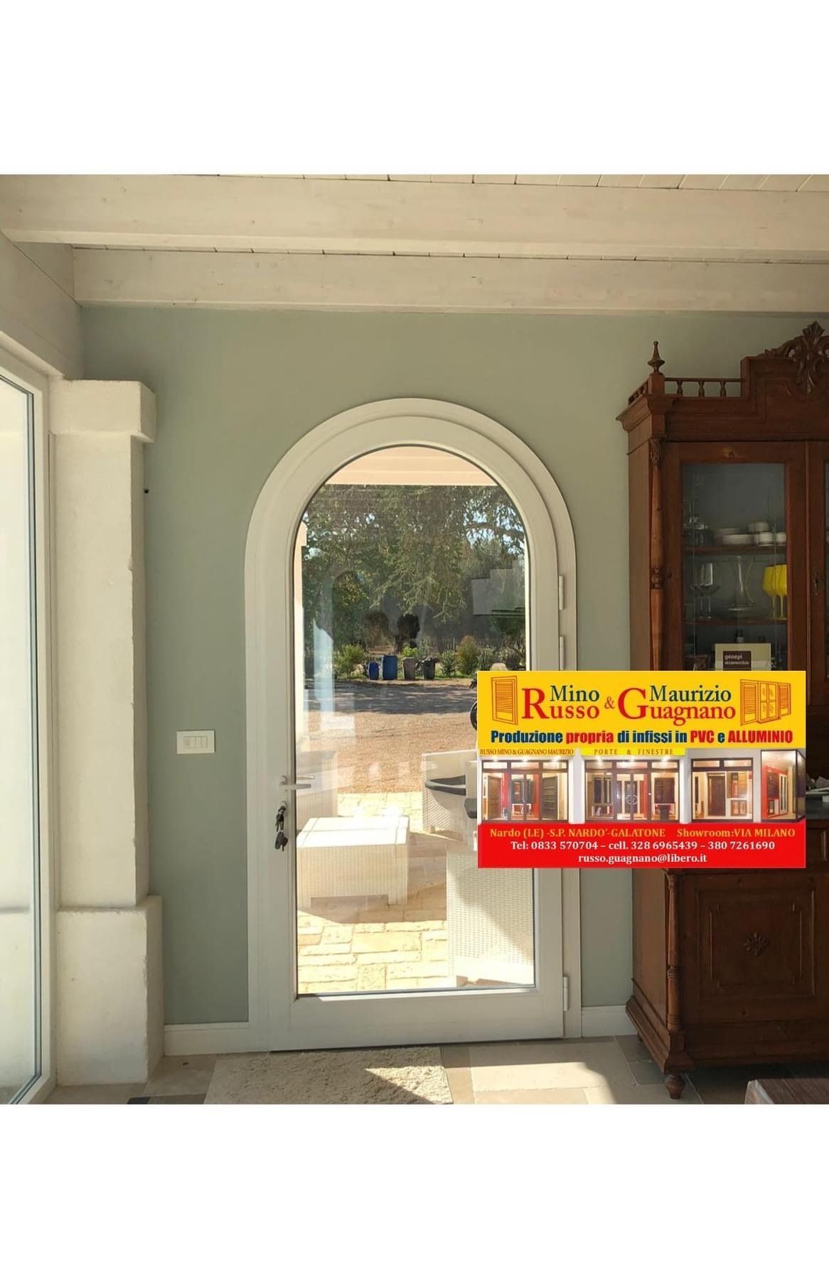 Porta a vetri ad arco in una stanza verde menta, con un mobile antico e una pubblicità.