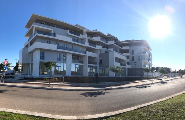 Moderno edificio a più piani con facciata bianca e grigia in una giornata di sole; vista d'angolo.
