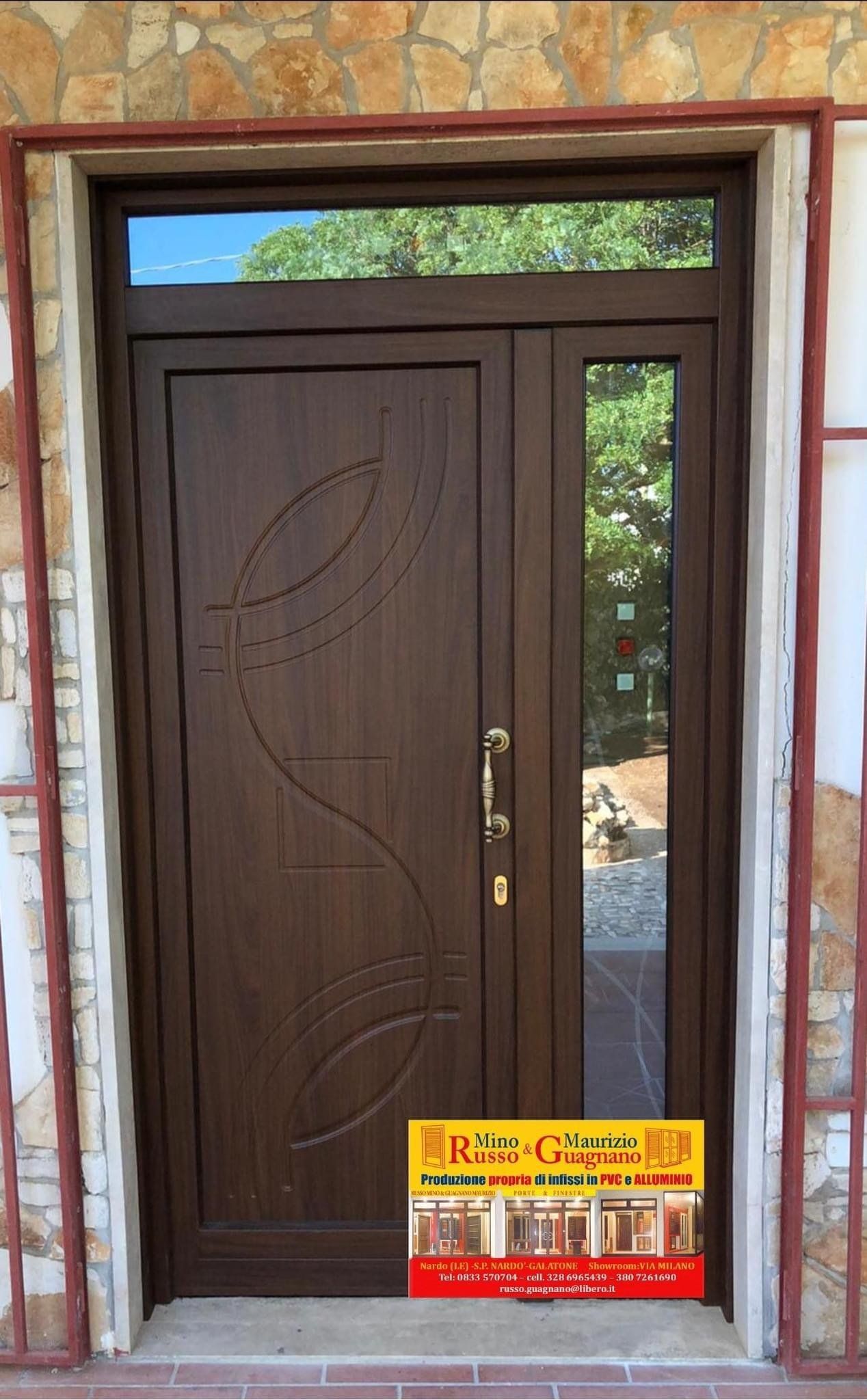 Porta d'ingresso marrone con pannello in vetro, vortici decorativi e un cartello pubblicitario sottostante.