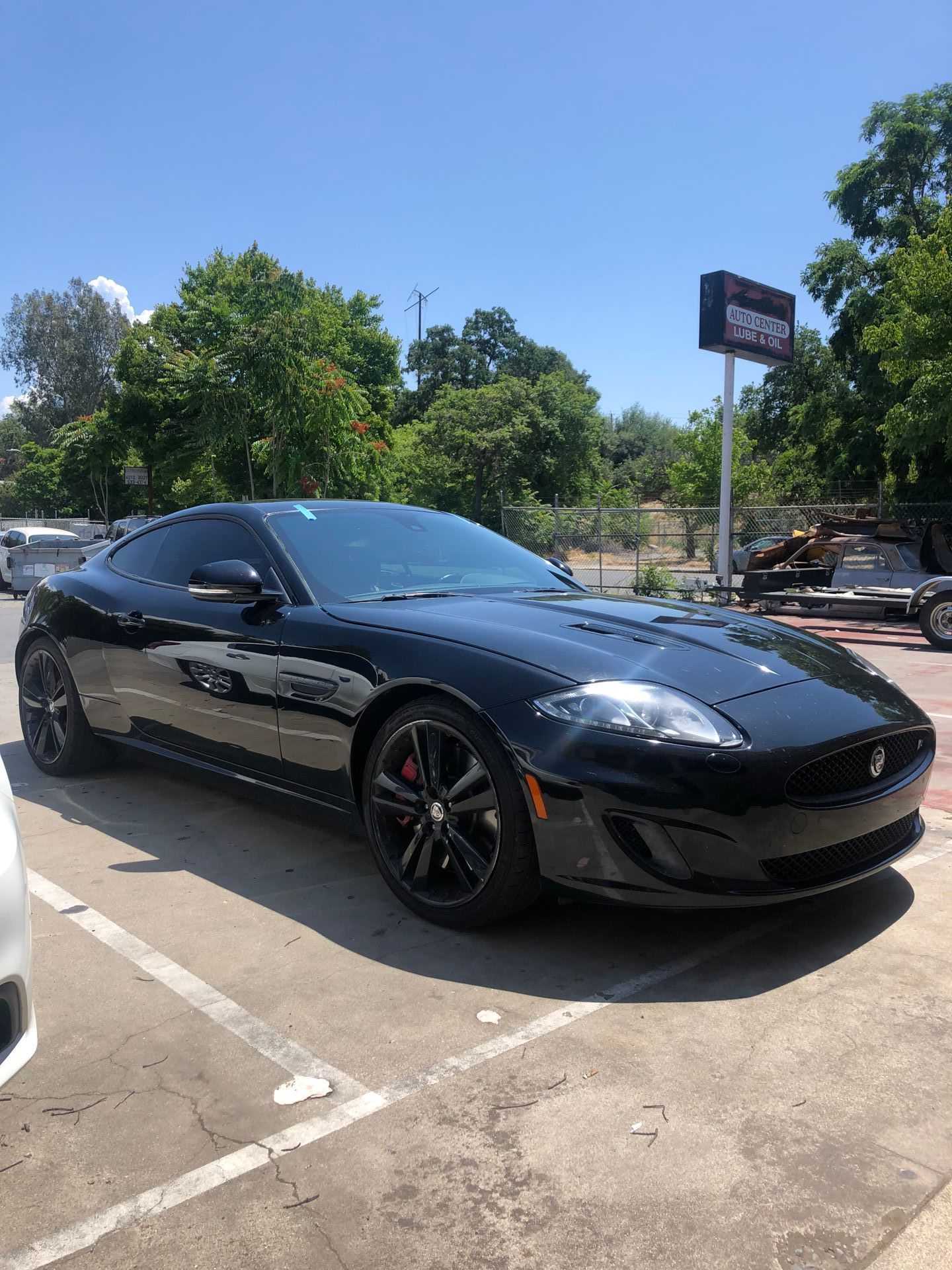 Black Jaguar sports car parked outside a building on a sunny day.