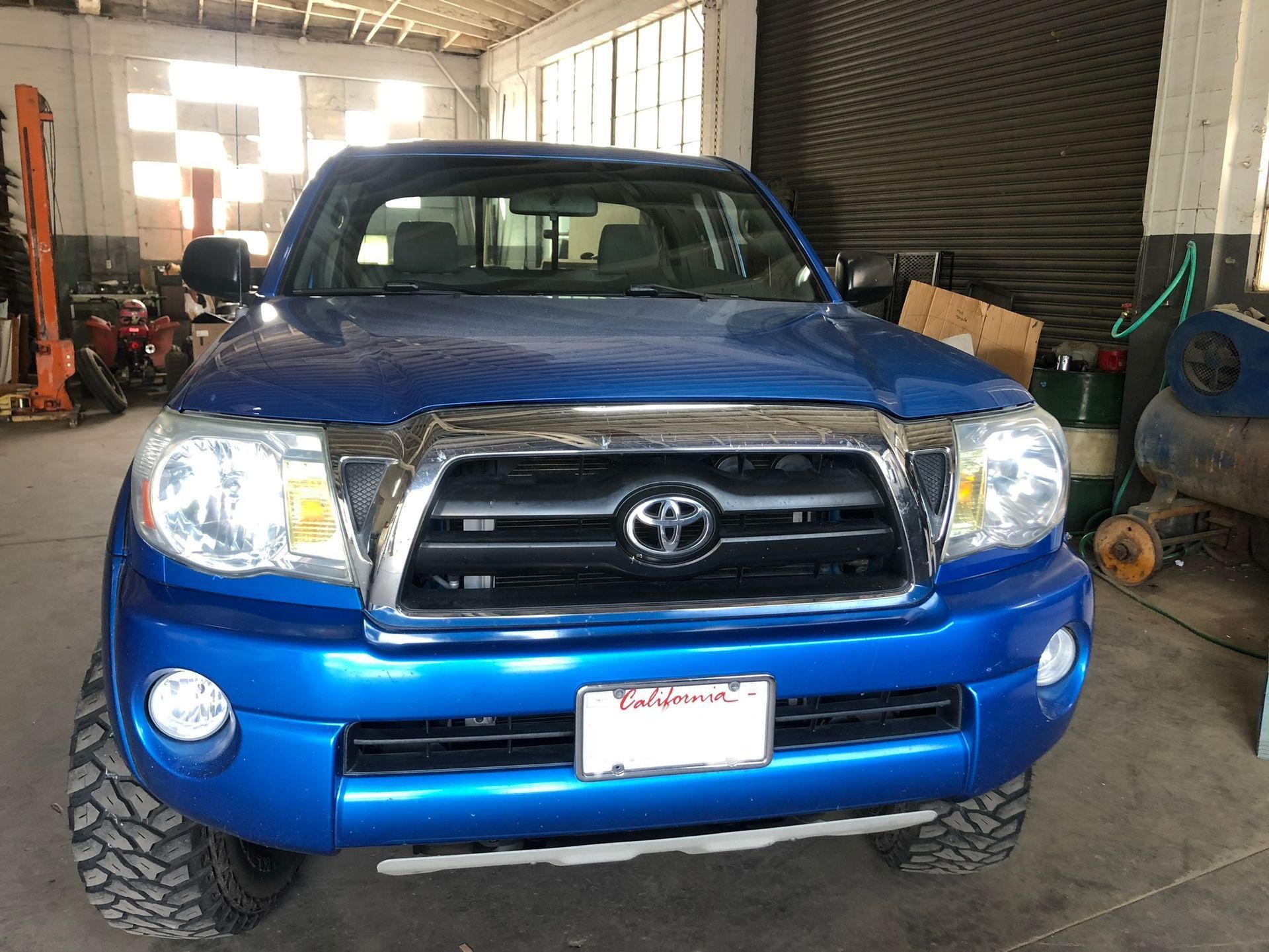 Blue Toyota Tacoma truck in a garage; front view.