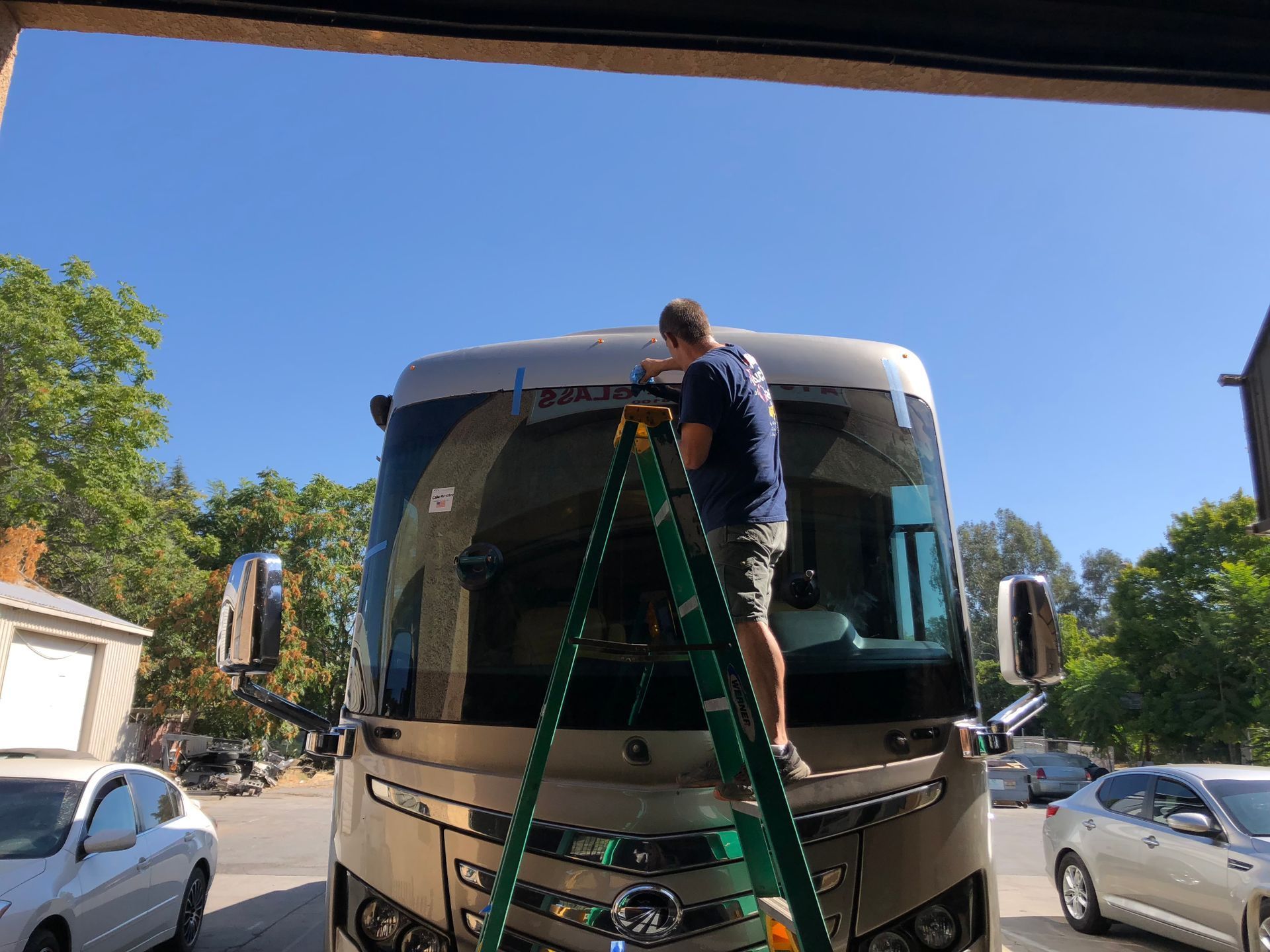 Mechanic applying sealant to a car windshield in a garage.