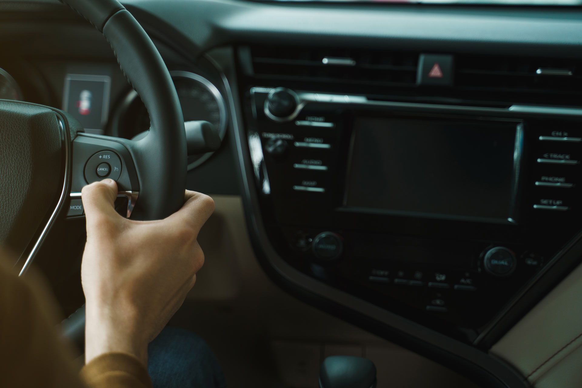 Person in gray work clothes using measuring tape and suction cup tool on a car windshield.