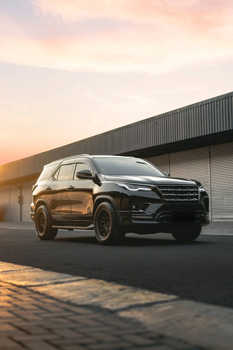 Black SUV parked near a building during sunset.