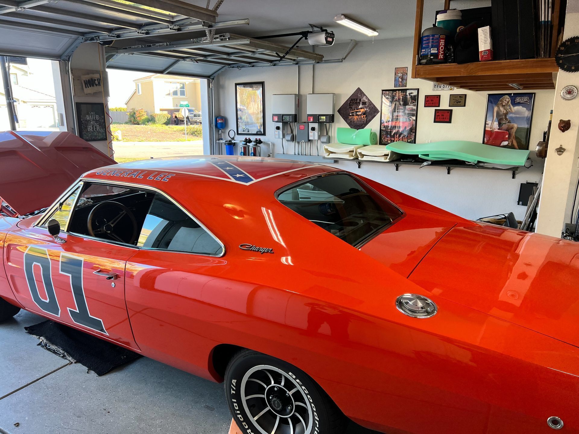 Bright orange General Lee Dodge Charger in a garage with the hood open.