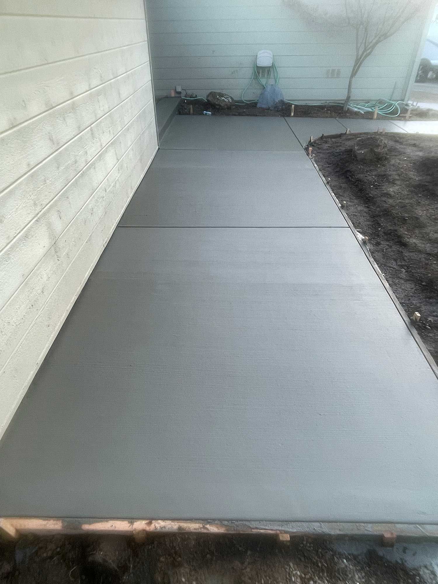 A concrete walkway is being built next to a house.