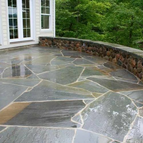 A stone patio with a stone wall surrounding it