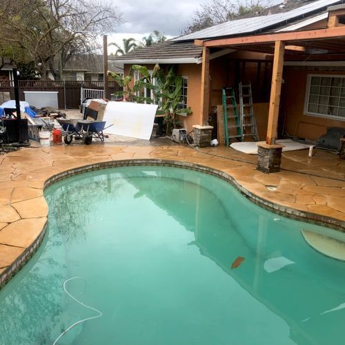 A large swimming pool with a house in the background