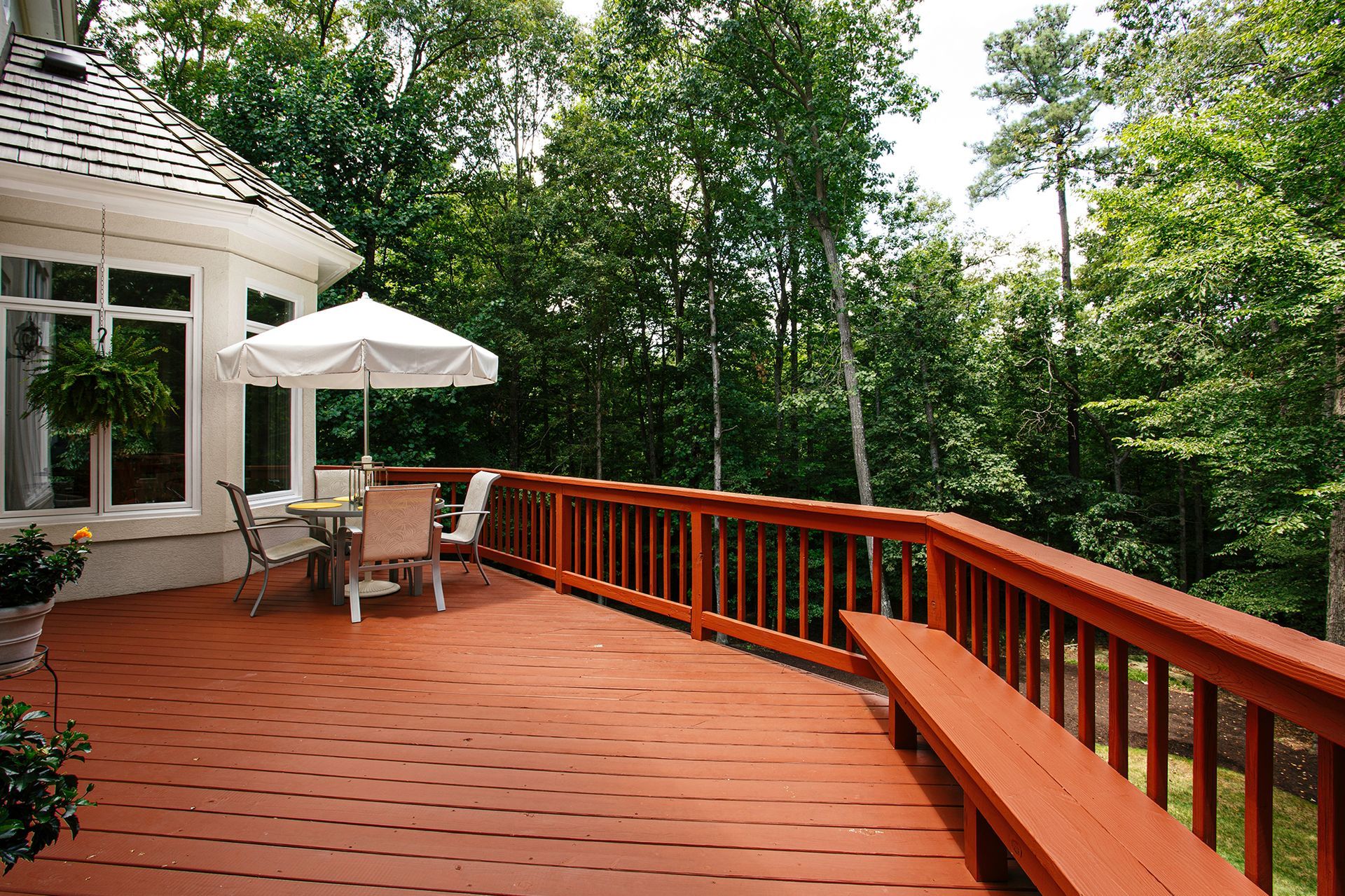 Wooden deck with patio furniture overlooking a lush green forest.