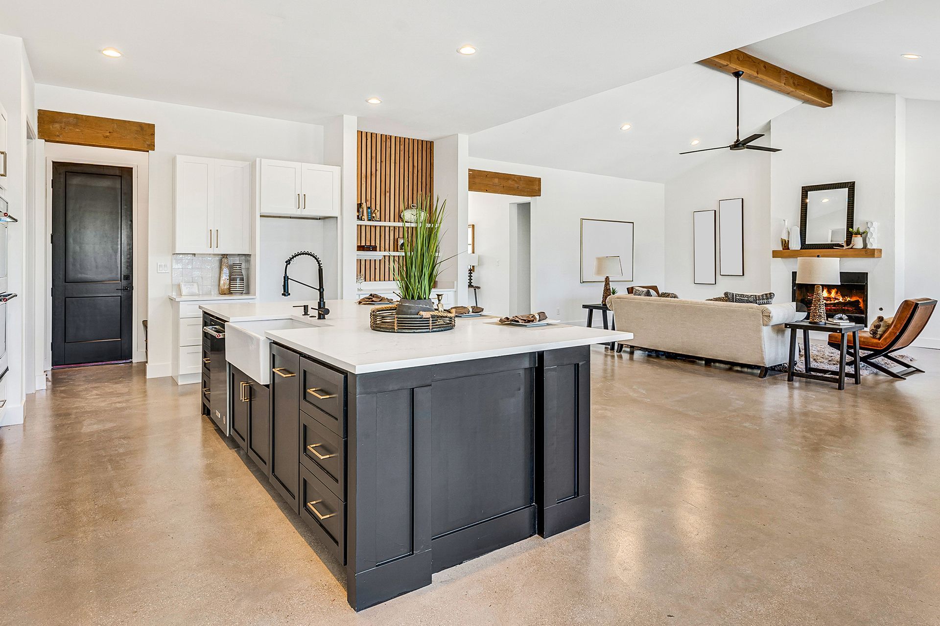 Open-concept kitchen with a large gray island, white cabinets, and a living room with a fireplace.