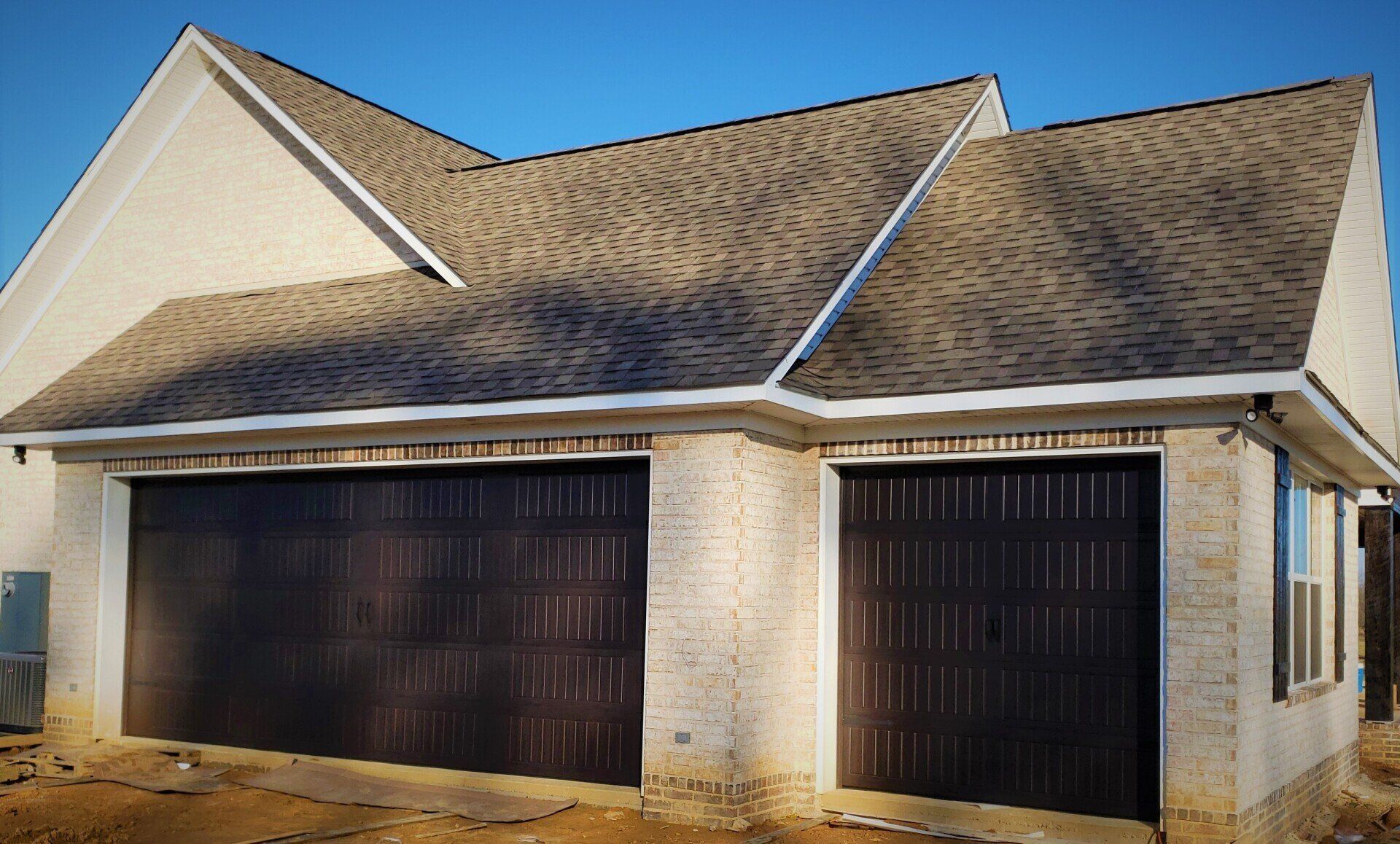 A white house with two garage doors and a gray roof