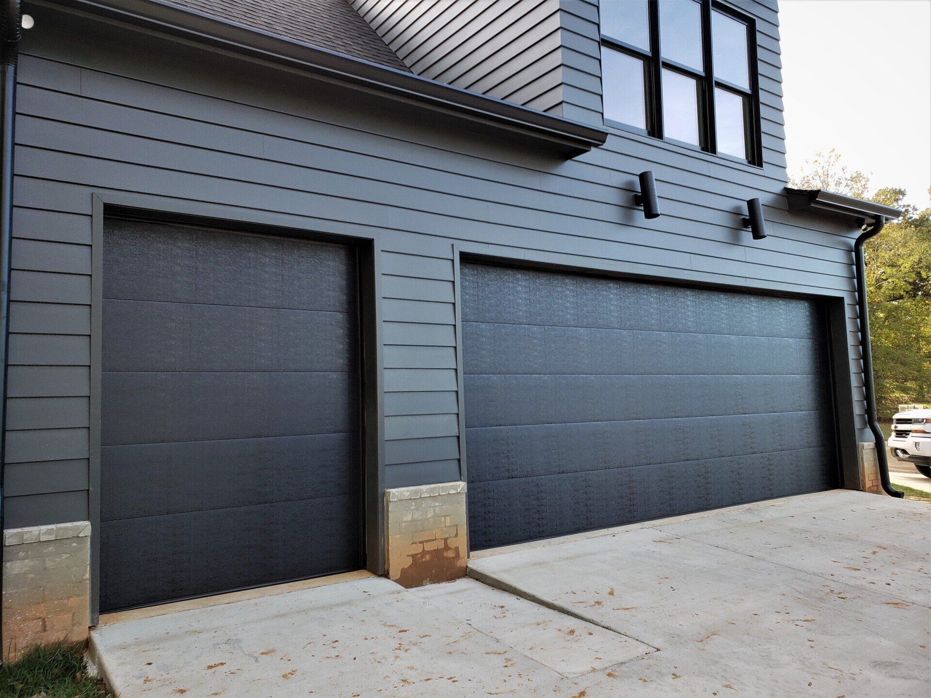 A large black garage door is on the side of a house.