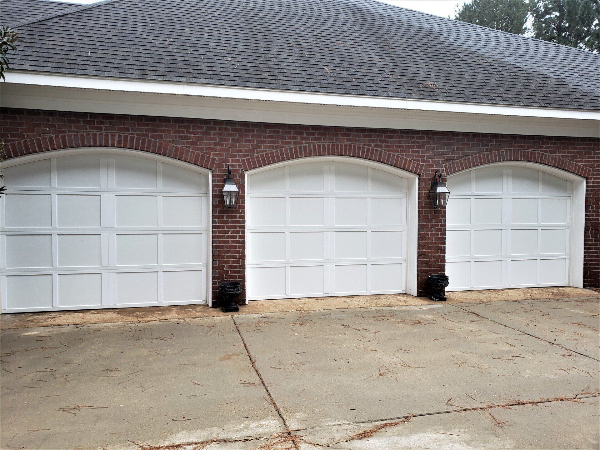 A row of white garage doors on a brick building.