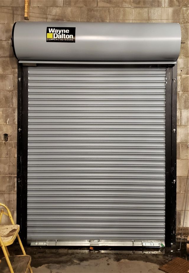 A gray garage door is sitting on top of a brick wall.