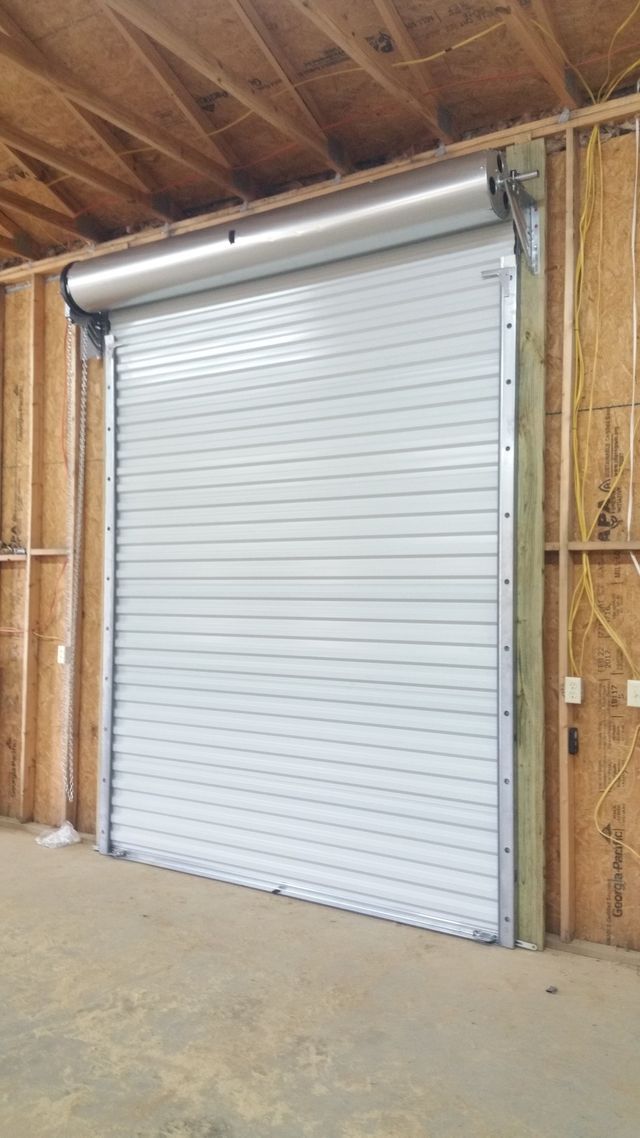 A large white garage door is in a building under construction.