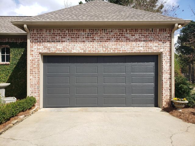 A brick garage with a dark gray garage door and concrete driveway.