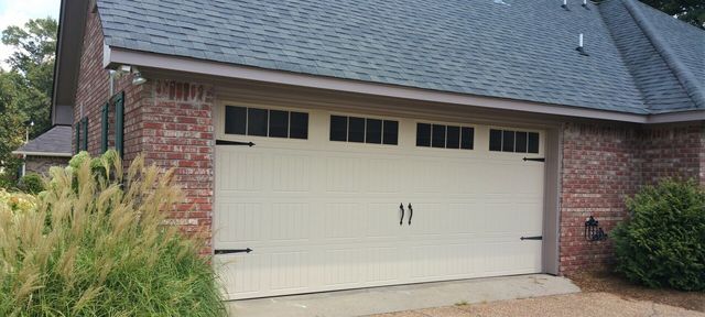 A white garage door is sitting in front of a brick house.