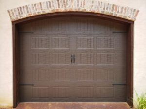 A brown garage door with a brick arch above it