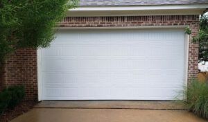 A white garage door is sitting in front of a brick house.