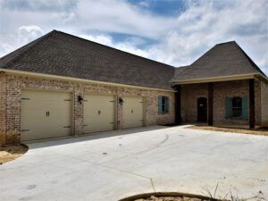 A large brick house with three garage doors and a driveway.