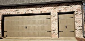 There are two garage doors on the side of a brick building.