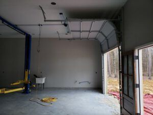 An empty garage with a lift and a door open.