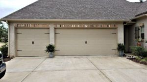 A car is parked in front of a house with three garage doors.