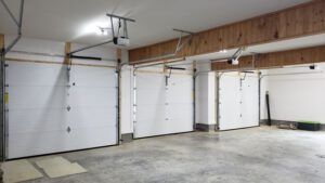 A large empty garage with three garage doors open.