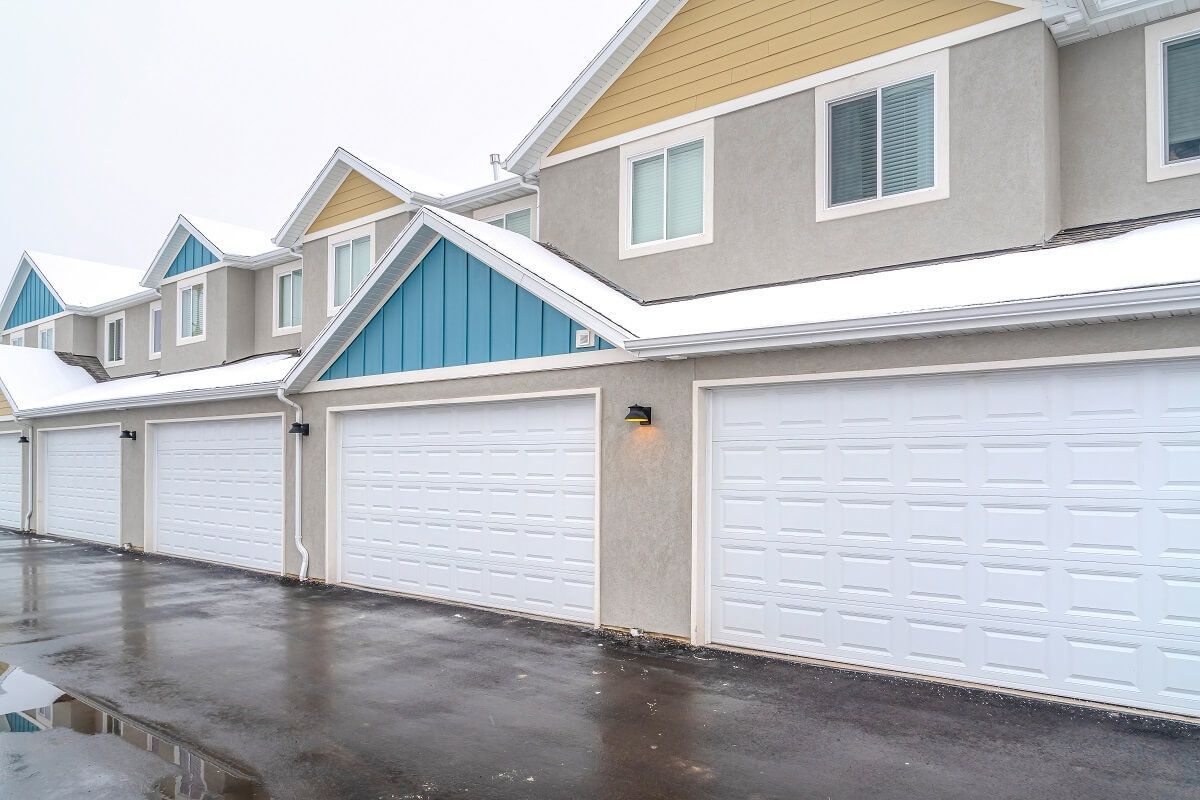 A row of houses with white garage doors and snow on the roofs