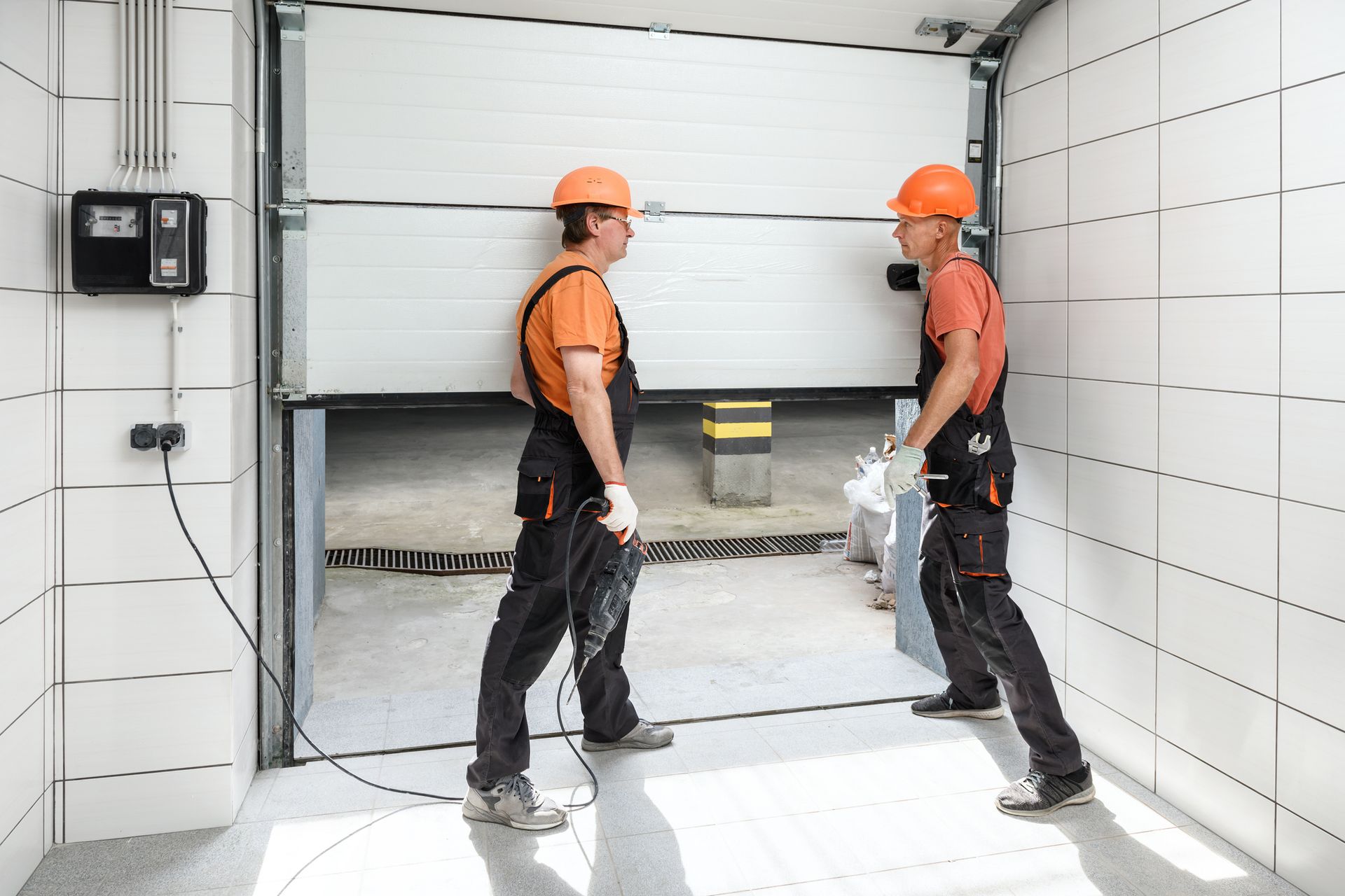 Two men are working on a garage door.