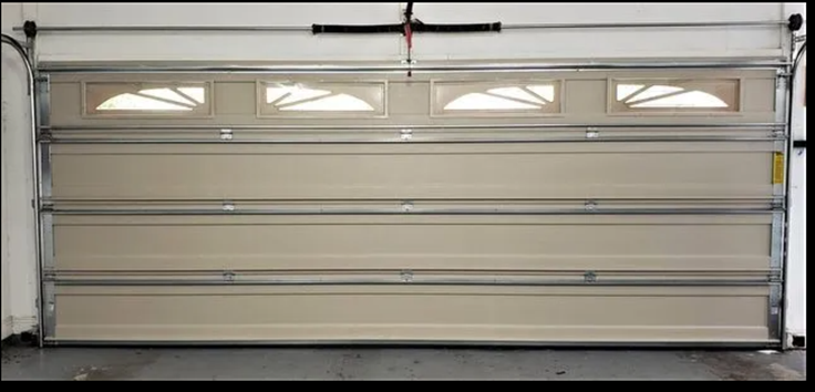 Closed beige sectional garage door with four rectangular windows.