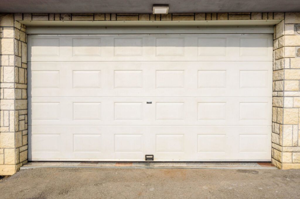 A white garage door is sitting in front of a brick wall.