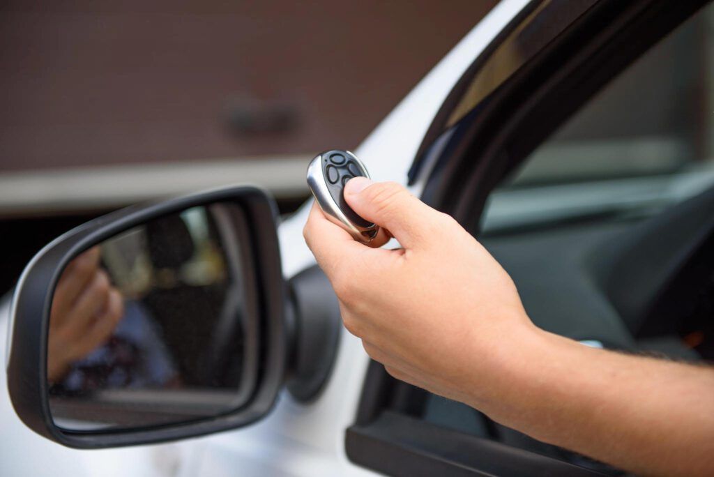 A person is holding a remote control in their hand while driving a car.