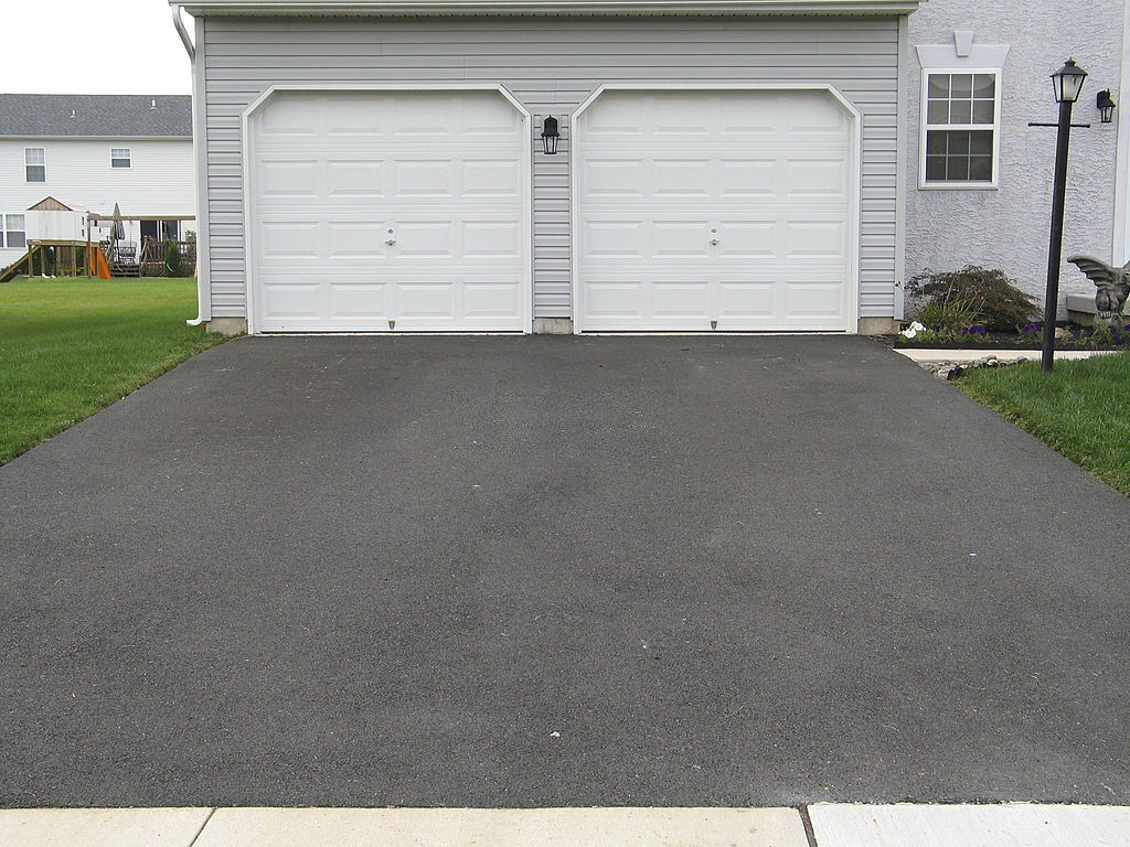 A driveway leading to a garage with two white garage doors