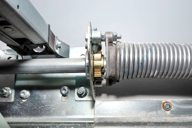 A close up of a garage door spring with a gear attached to it.